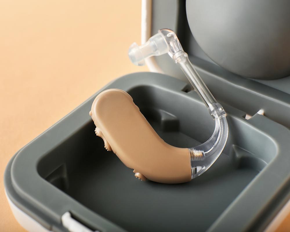 Box with hearing aid on color background, closeup